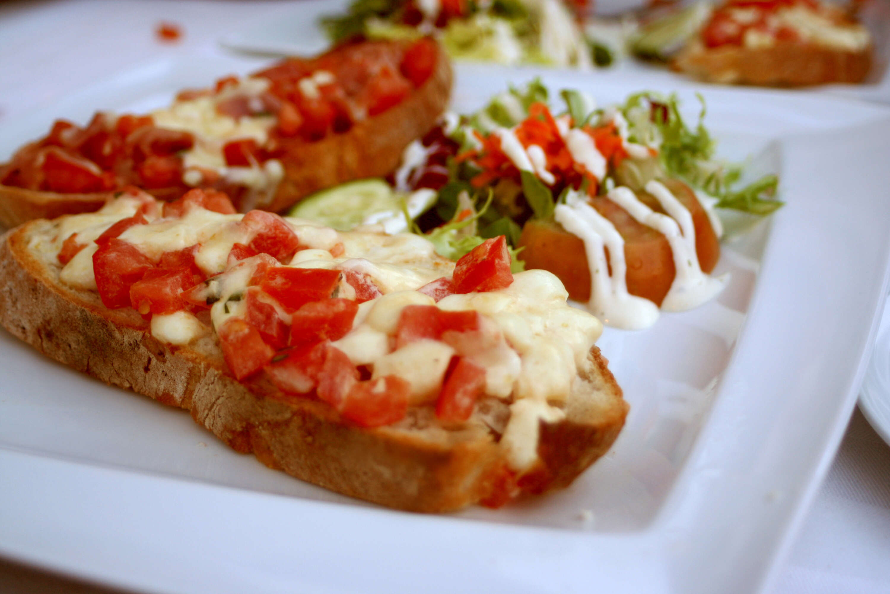 Bruschetta mit Tomaten, Käse und Salat auf Teller