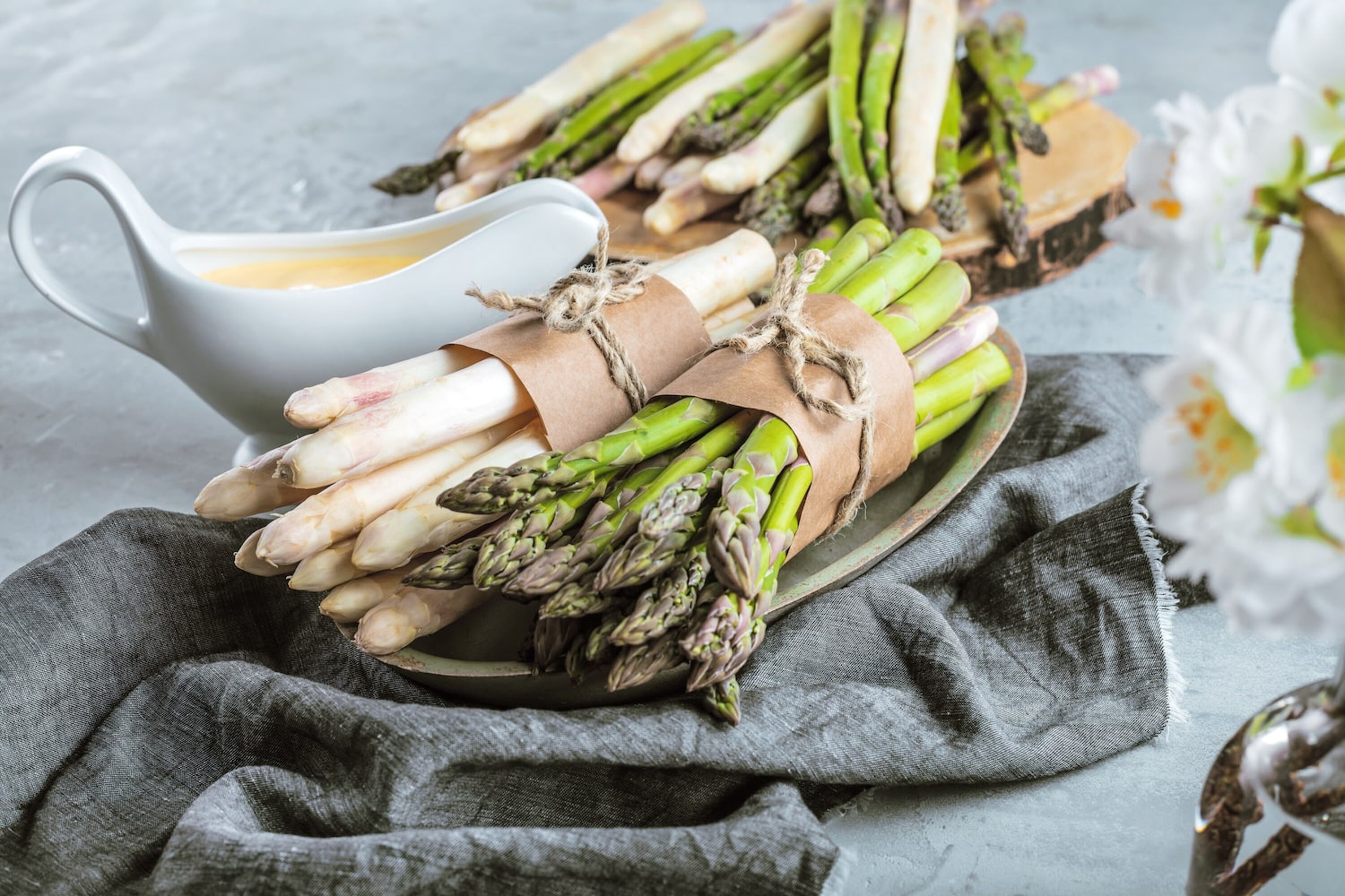 Grüner und weißer Spargel im Bund auf einem Teller mit Sauce Hollandaise