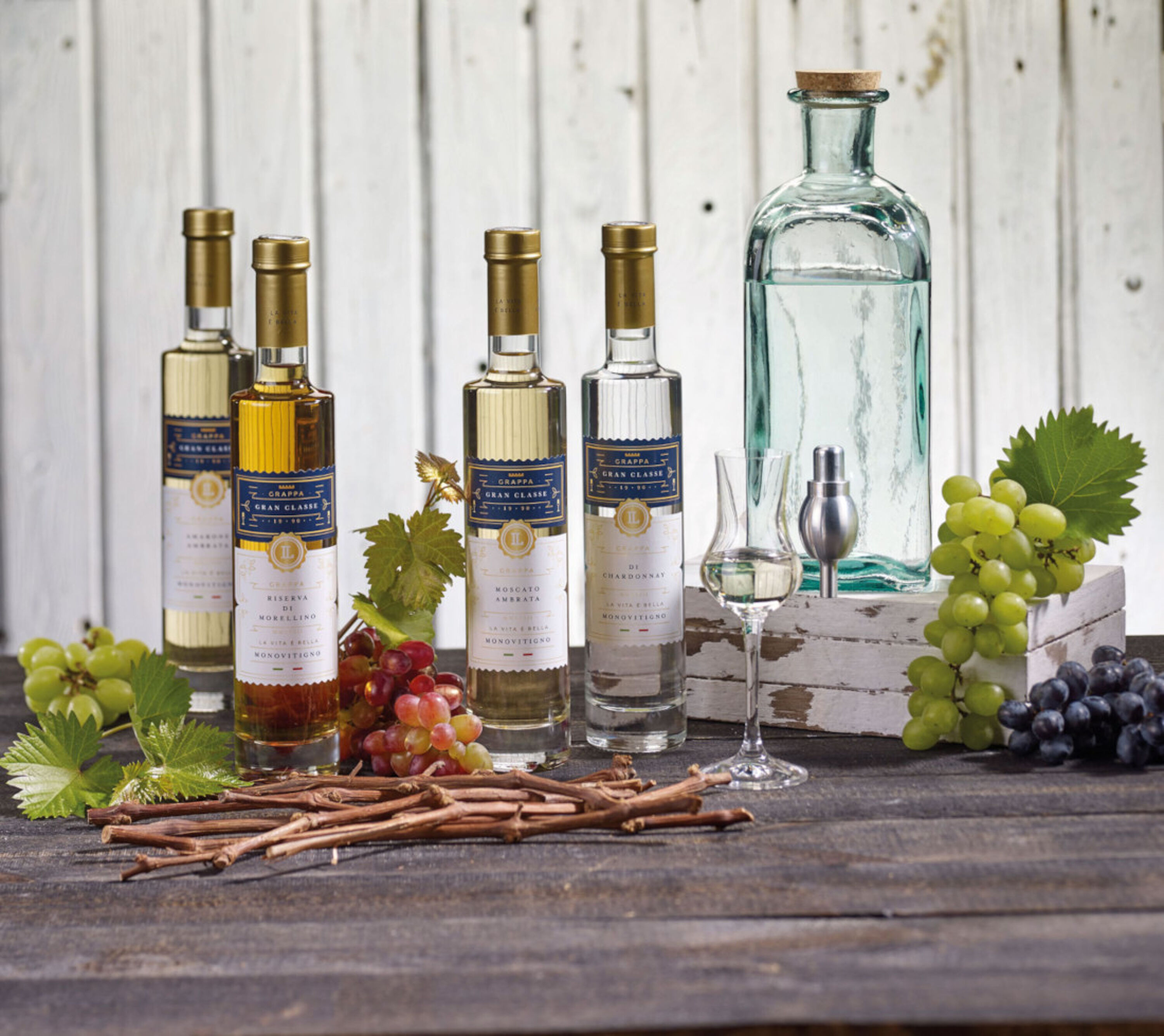 Vier Sorten LAUX Grappa auf Tisch neben Trauben